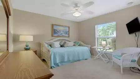 Cozy bedroom with a daybed, TV, and views of the greenery.