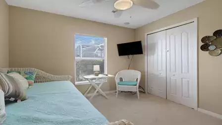 Cozy guest bedroom with a daybed, TV, and a seating area by the window.