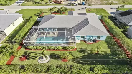 Spacious, well-kept garden with palm trees and screened pool area
