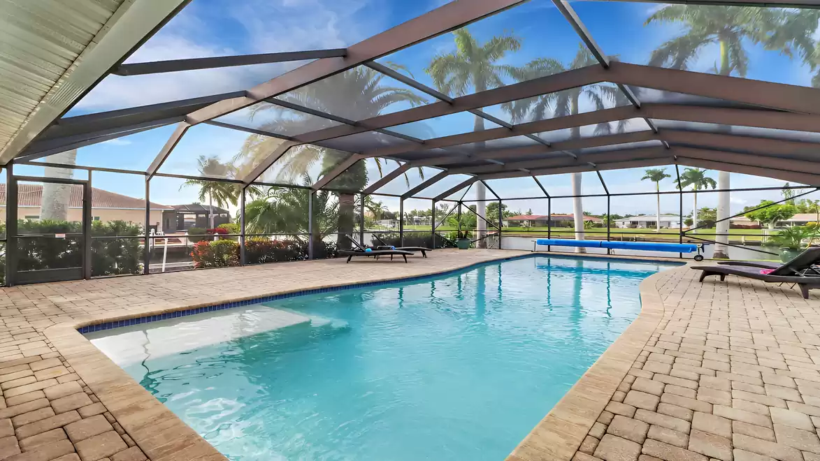 Screened pool area with spacious swimming pool, loungers, and canal view in Cape Coral