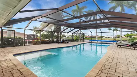 Screened pool area with spacious swimming pool, loungers, and canal view in Cape Coral