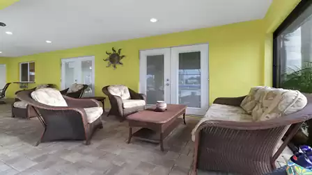 Cozy covered patio with rattan seating area and view of the pool area.