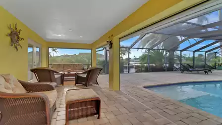Covered patio with seating area and direct access to screened pool area overlooking the canal.