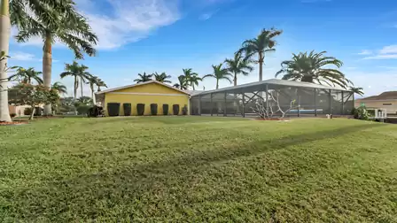 Well-maintained backyard with green lawn and view of the villa's screened pool area.