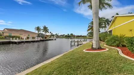 View of the well-maintained garden along the canal with boat dock and tropical landscaping - direct waterfront location.