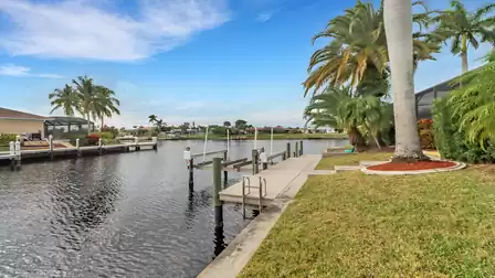 Private boat dock with ladder on the canal, surrounded by palm trees and well-kept lawn - perfect waterfront access.
