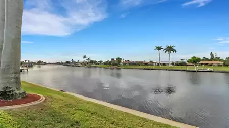 Wide canal with palm trees along the shore and manicured lawn in the foreground - view facing southwest.