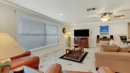Bright living room with comfortable seating, flat-screen TV, and ceiling fan - the perfect place to relax after a sunny day.