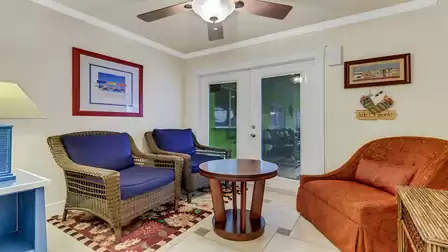 Cozy sitting area with wicker chairs, colorful decor, and access to the patio.