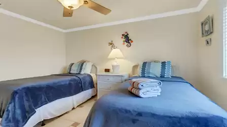 Guest bedroom with two twin beds, wicker nightstand, and coastal-inspired décor.