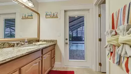 Modern bathroom with granite vanity and direct access to the pool area - perfect for a refreshing rinse after a swim.