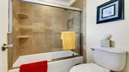 Second bathroom featuring a stylishly tiled tub/shower combo with sleek glass enclosure - perfect for relaxing baths or quick showers.
