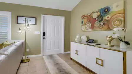 Modern entryway with bright door, stylish sideboard, and colorful wall art in a vacation home in Cape Coral.