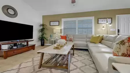 Cozy living area with large flat-screen TV, elegant decor, and L-shaped beige leather sofa