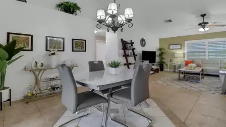 Modern dining area with glass table, leather chairs, and stylish bar cart decor against a light wall