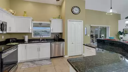 Modern kitchen with white cabinetry, granite countertop and view towards the patio