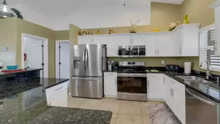 Modern kitchen with white cabinets, granite countertops, and stainless steel appliances