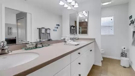 Bright bathroom with double vanity, large mirror and natural light window