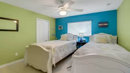 Cheerful bedroom with two white twin beds and colorful green and blue accent walls
