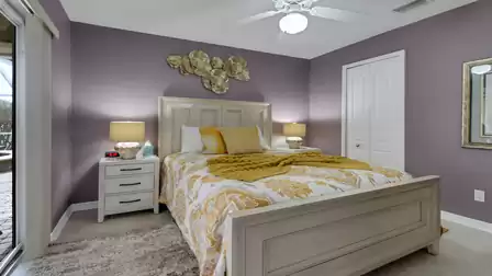 Cozy bedroom with stylish purple accent wall, double bed with yellow decor and direct access to the patio