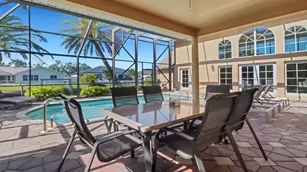 Dining table with chairs in the covered patio area by the screened pool with canal view