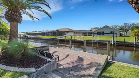 Seating area at the boat dock with palm trees and view of a wide canal in Cape Coral.