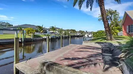 Boat dock with canal view, surrounded by palm trees and manicured lawns.