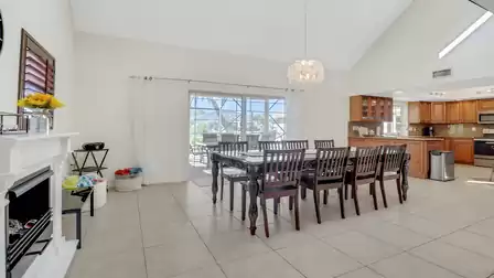 Spacious open dining area with dark wood table for ten guests, view of the covered terrace, and adjacent kitchen with granite countertops.