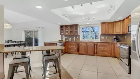 Spacious kitchen with granite countertops, bar area, and view of the dining table and terrace with fireplace in the background.