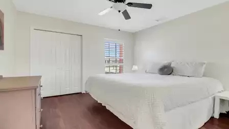 Bedroom with king-size bed, ceiling fan, and window overlooking the outside.
