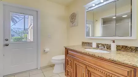 Bathroom with granite vanity, large mirror, and access to the poolside patio.