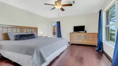 Bright bedroom with king-size bed, dresser, TV and patio access.