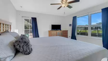Bedroom with large bed, ceiling fan, TV and canal view.