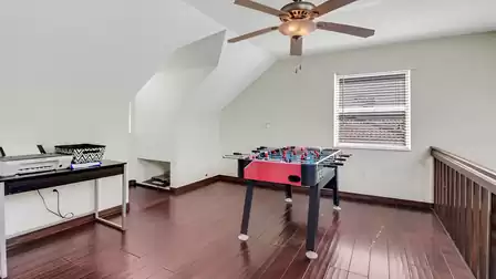 Bright hobby room with ceiling fan, foosball table and desk with printer.
