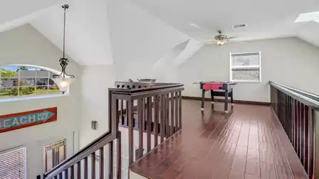 Open gallery with view to the ground floor, wooden flooring, foosball table and desk under the sloped ceiling.