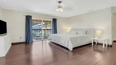 Spacious bedroom with king-size bed, ceiling fan, and access to the covered balcony.