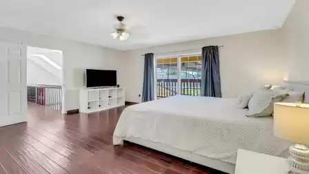 Bright bedroom with king-size bed, TV area, and access to the balcony overlooking the canal.
