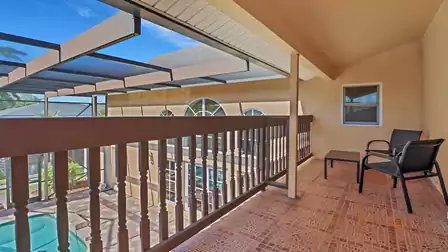 Covered balcony with seating area overlooking the pool area.