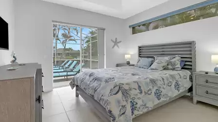 Bright guest bedroom with nautical bedding and direct access to the pool terrace overlooking the canal.
