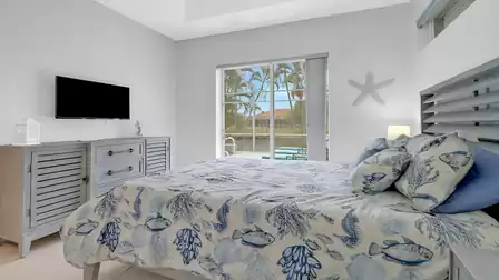 Guest bedroom with cozy bed, decorative starfish on the wall, and a beautiful view of the canal-side terrace.