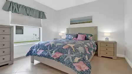 Cozy bedroom featuring ocean-themed bedding, two nightstands, and a window overlooking the garden.