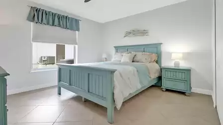 Bright bedroom featuring a turquoise bed frame and matching coastal-style nightstands.