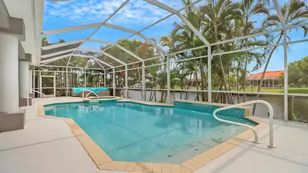 View of the spacious pool and spa area with lounge seating and palm trees by the waterfront