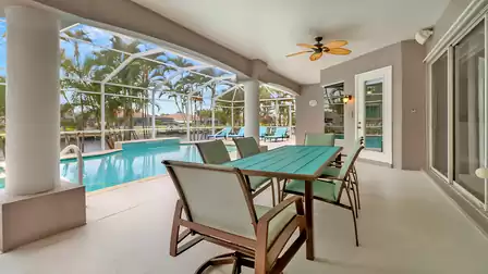 Covered terrace with dining table and view of the pool and canal - perfect for outdoor meals.