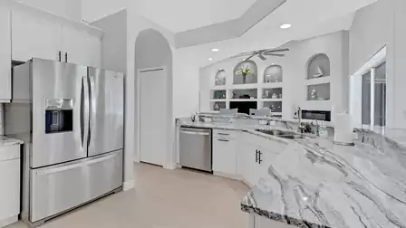 Modern kitchen with bright cabinets, stainless steel appliances and granite countertops, adjacent to the living area.