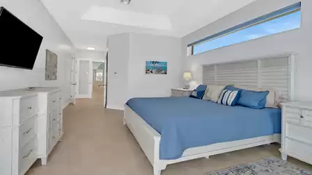 Master bedroom with elegant design, TV, nightstands, and dresser - ideal for relaxing evenings.