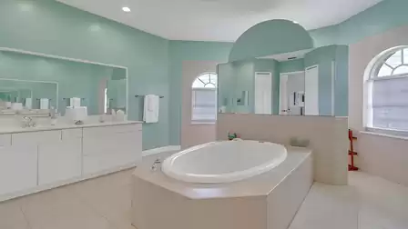 Luxurious bathroom with oval bathtub, double sinks, and a stylish aqua-green color scheme