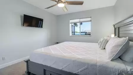 Bedroom with ceiling fan, gray bed and window overlooking the canal