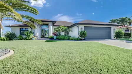Villa Leykia Cape Coral vacation home exterior with large lawn, palm trees and driveway
