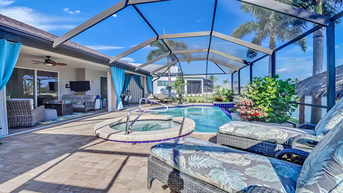 Covered patio featuring a cozy lounge, dining table, and view of the pool with spa.